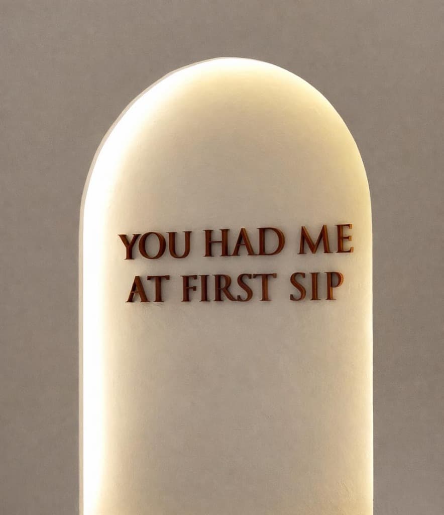 Close-up of the arched 'YOU HAD ME AT FIRST SIP' wall sign.